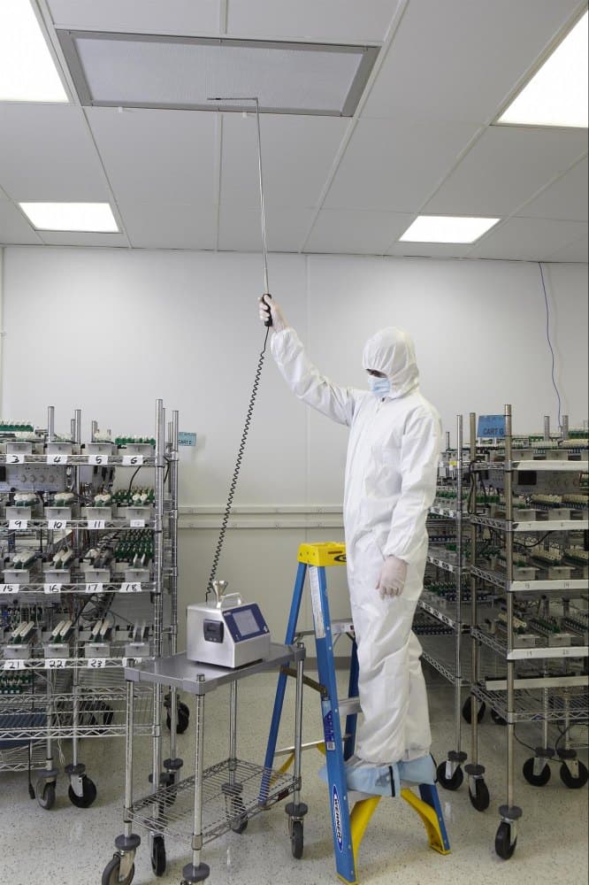 Tekniker utför luftprovtagning med prob vid HEPA-filter i renrum – mikrobiologisk övervakning