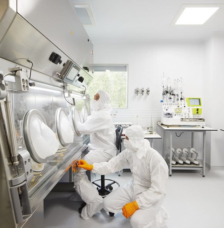 Två tekniker vid isolator i farmaceutiskt renrum – GMP-produktion med luftövervakning